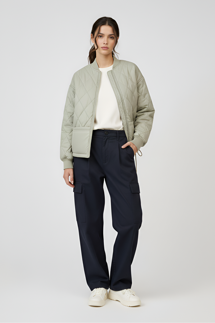 Woman wearing a light green puffer jacket and dark blue pants on a white background