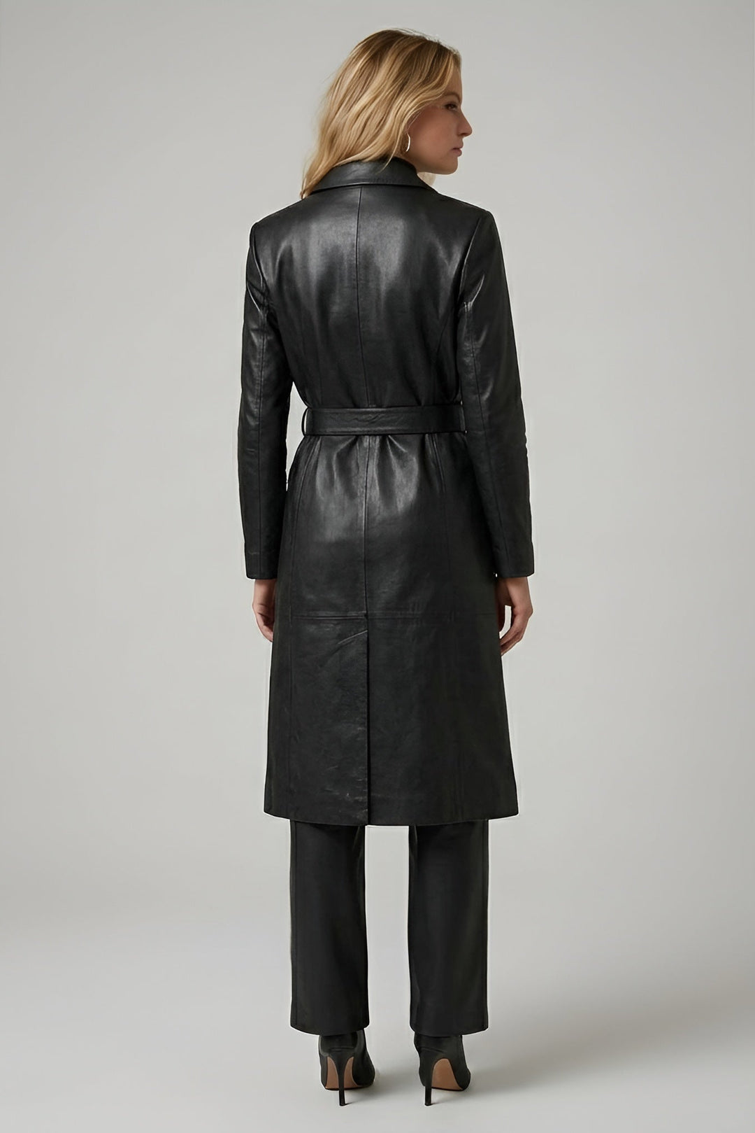 Woman wearing a black leather trench coat on a gray background