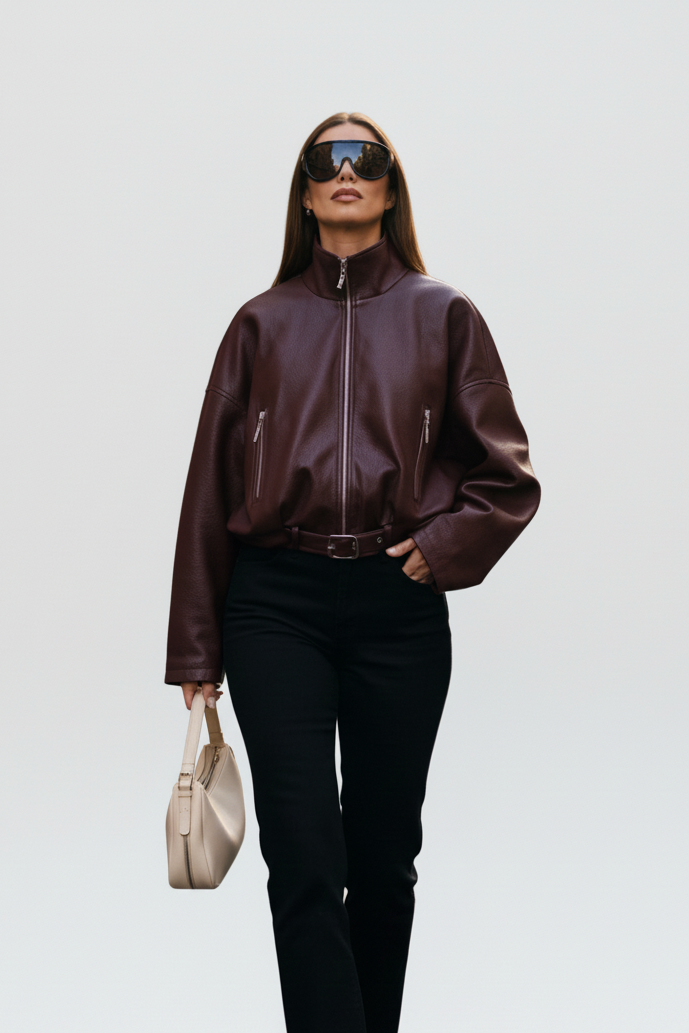 Woman wearing AVELON Faux Leather Bomber Jacket in burgundy with funnel neck and zip front.