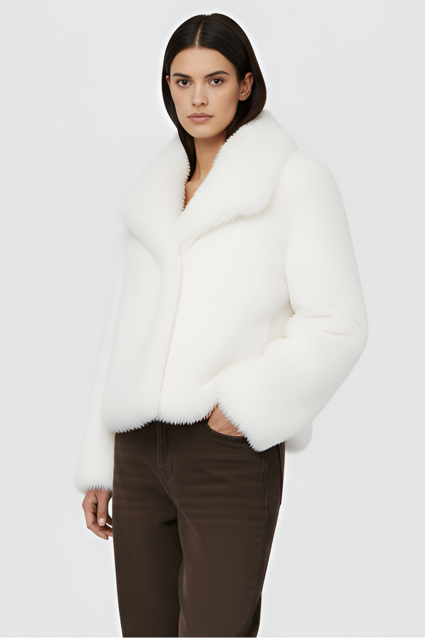 Woman wearing a white fur coat over a white outfit on a plain background