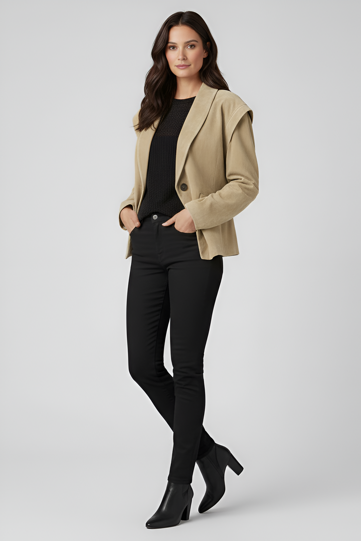 Woman wearing a beige blazer over a black top and pants on a white background