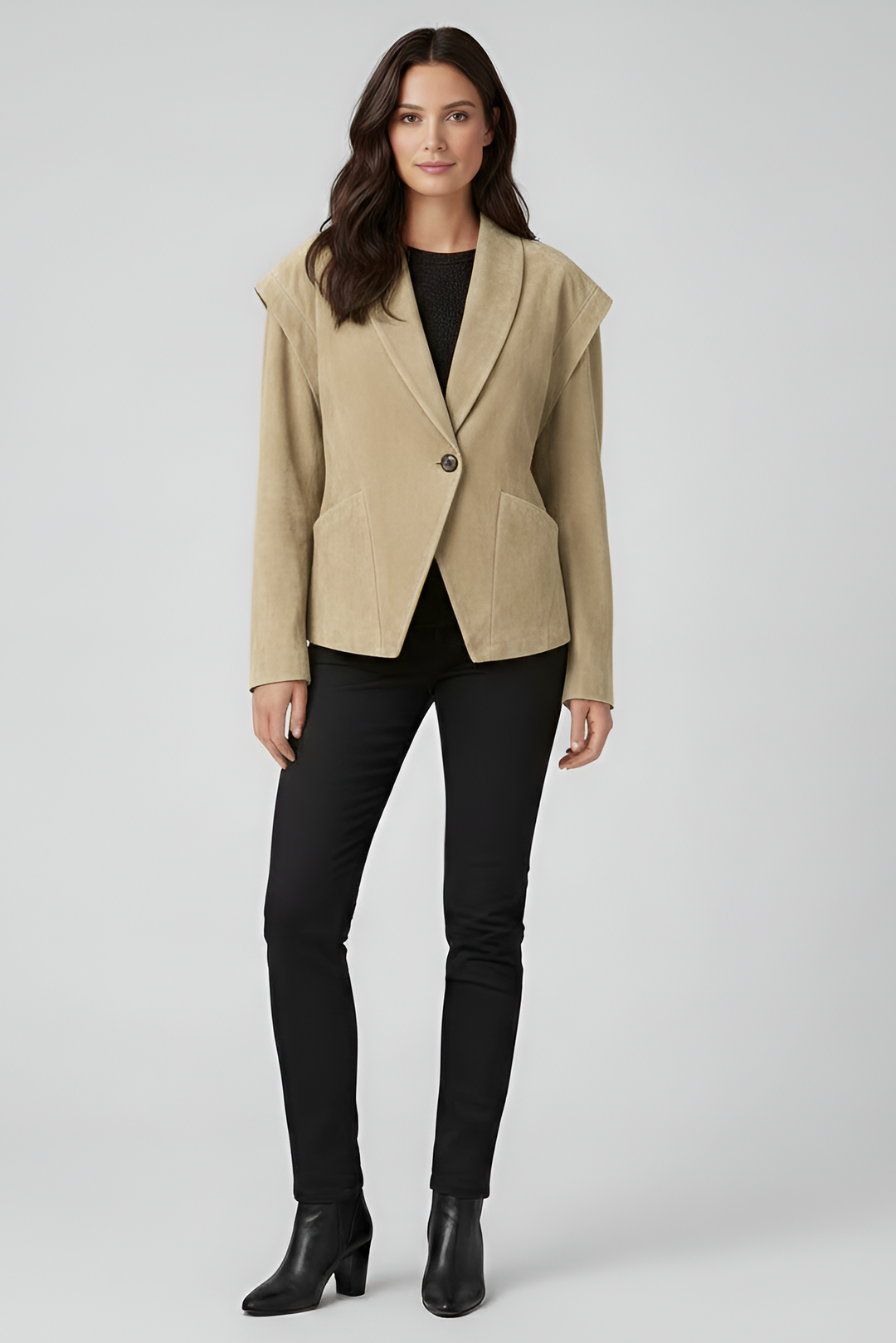 Woman wearing a beige blazer over a black top and pants on a white background