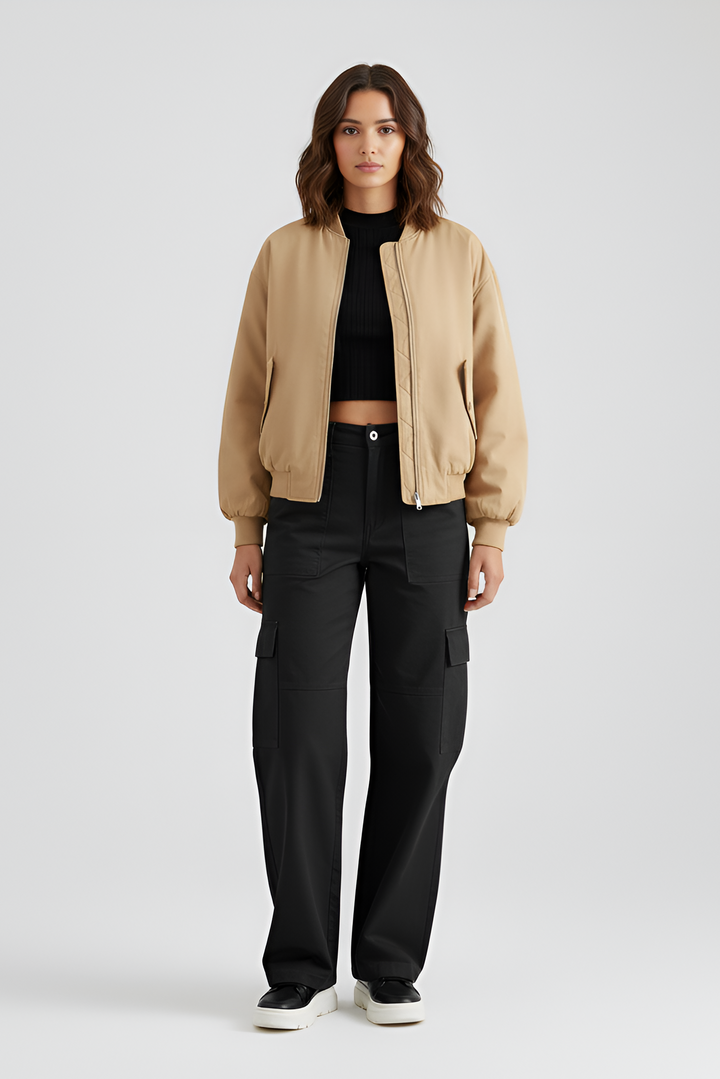 Woman wearing a beige bomber jacket and black cargo pants on a white background