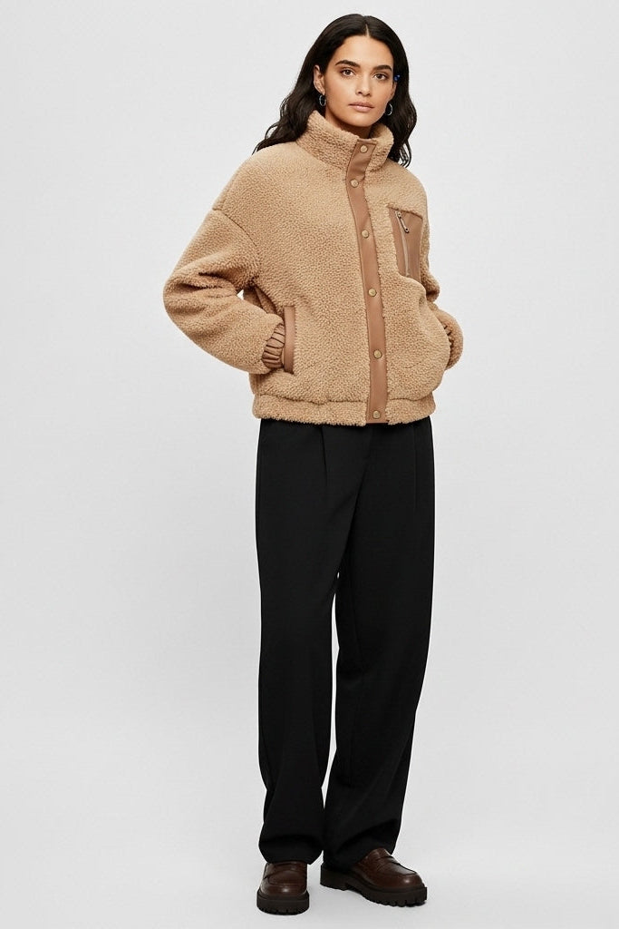 Woman wearing a beige jacket and black pants on a white background