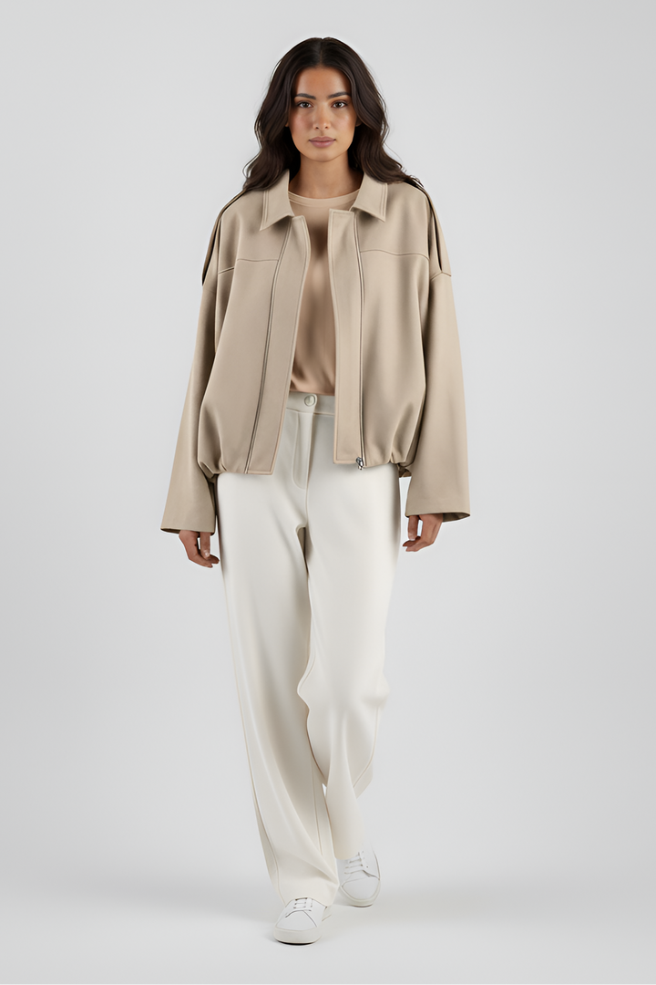Woman wearing a beige jacket and white pants on a white background