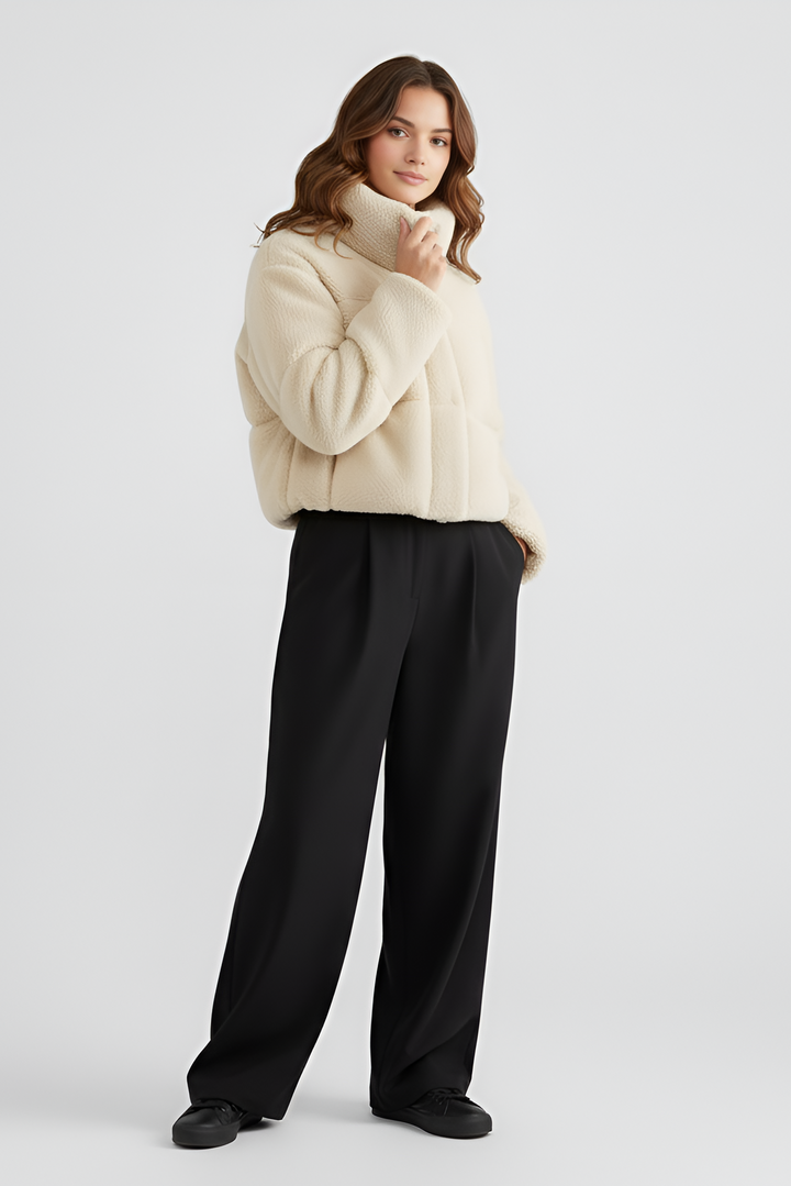 Woman wearing a beige puffer jacket and light blue jeans on a white background