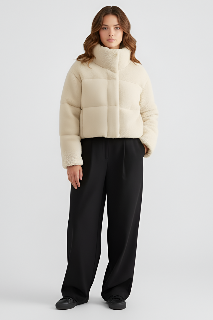 Woman wearing a beige puffer jacket and light blue jeans on a white background