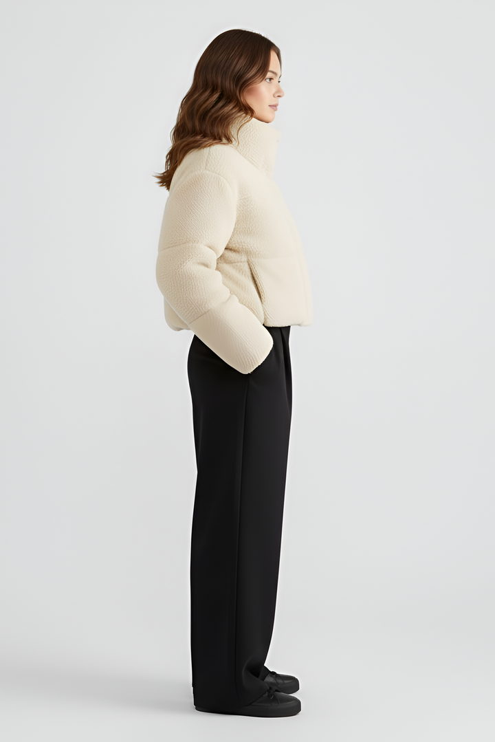Woman wearing a beige puffer jacket and light black pants on a white background