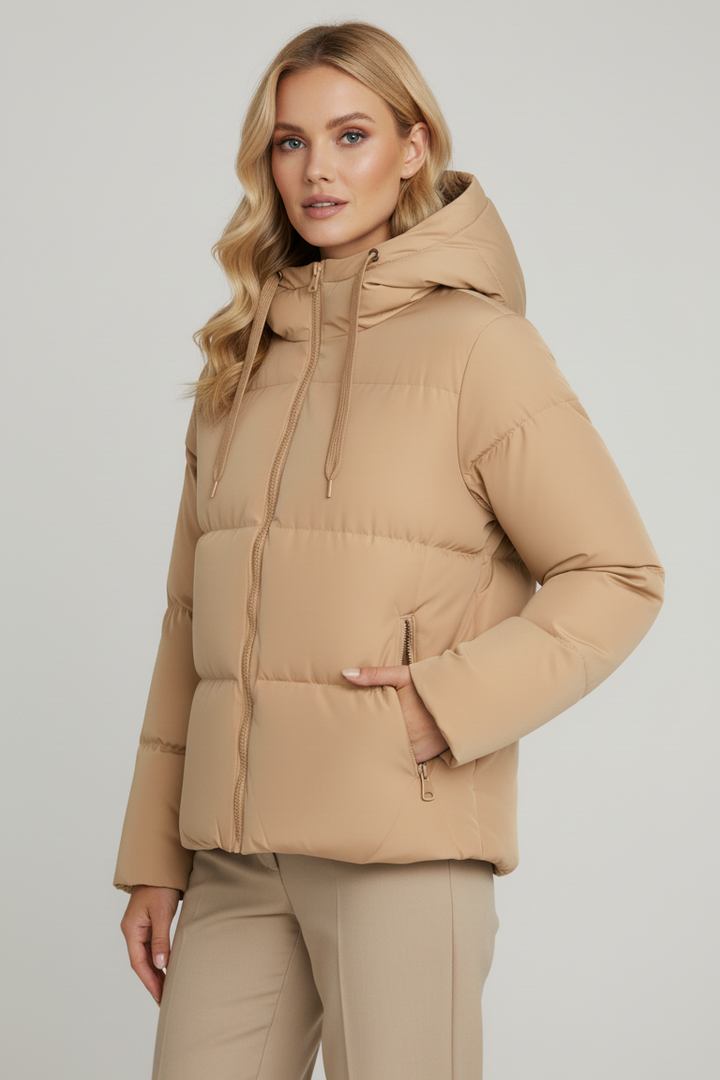 Woman wearing a beige puffer jacket on a plain background