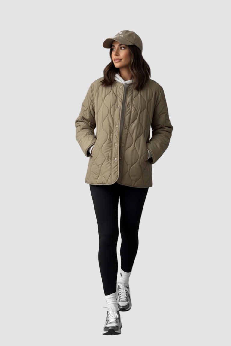 Woman wearing a beige quilted jacket, black leggings, and white sneakers on a gray background