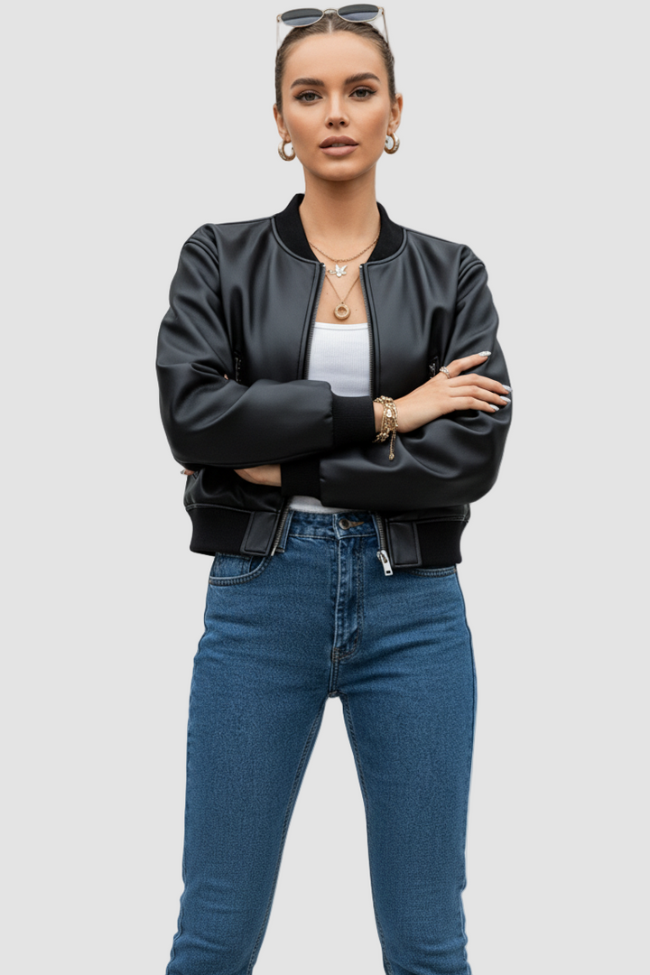 Woman wearing a black bomber jacket and blue jeans on a gray background