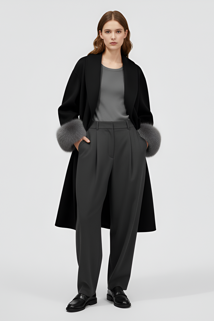 Woman wearing a black coat with fur cuffs and gray pants on a white background
