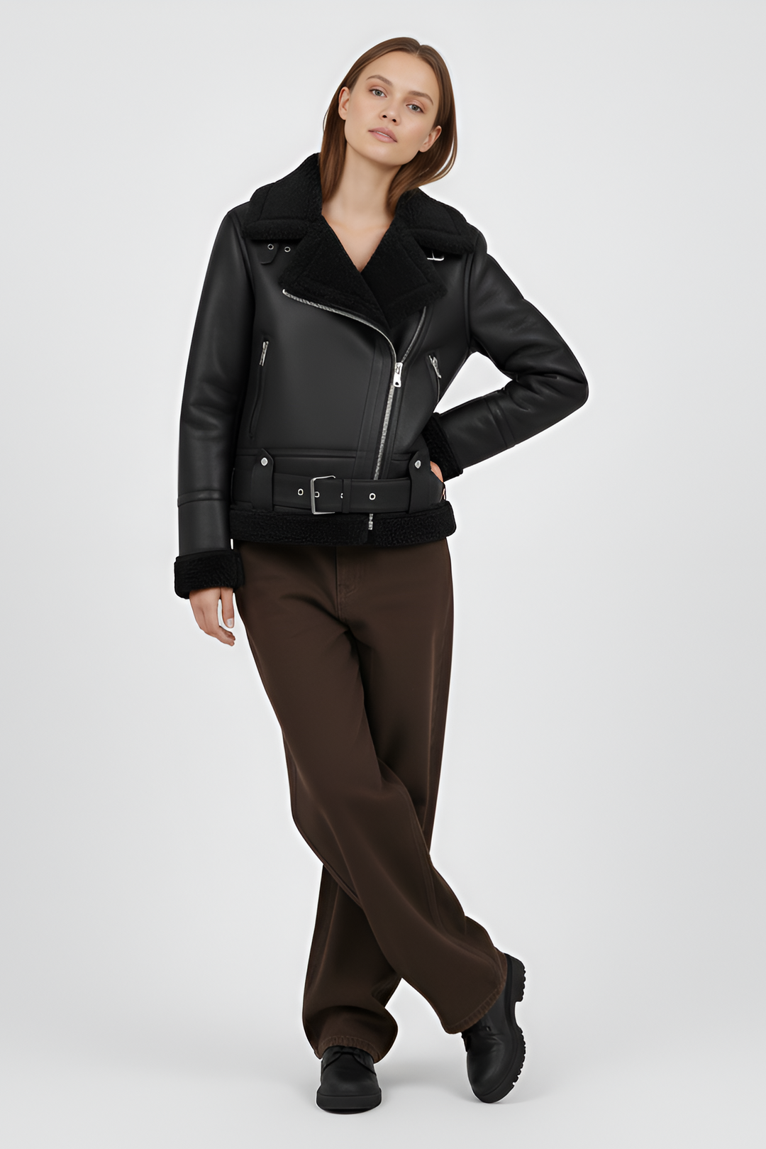 Woman wearing a black shearling jacket and pants on a light gray background