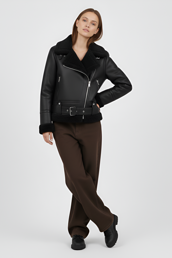 Woman wearing a black shearling jacket and pants on a light gray background