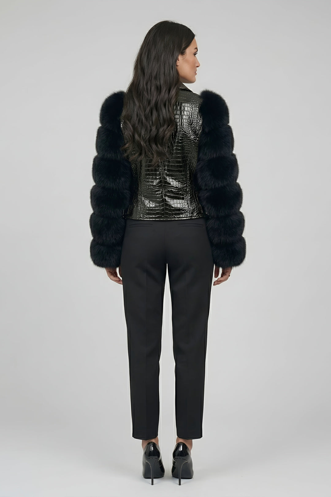 Woman wearing a black fur coat with a sequined back on a gray background