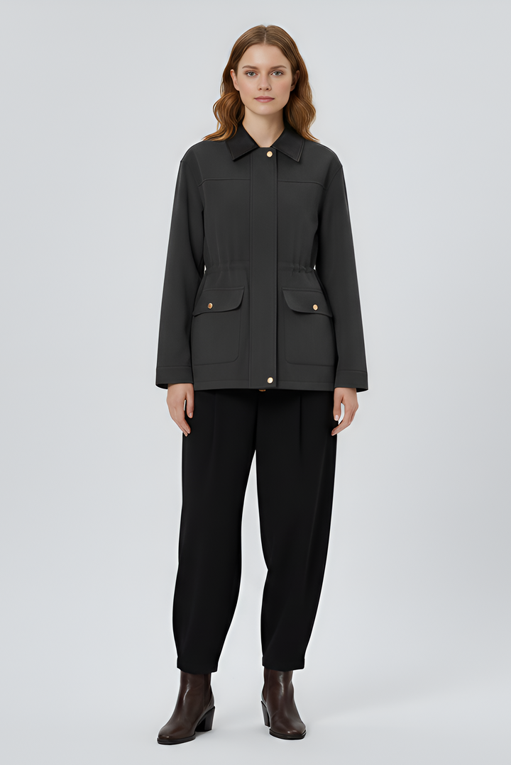 Woman wearing a black jacket and pants on a light gray background