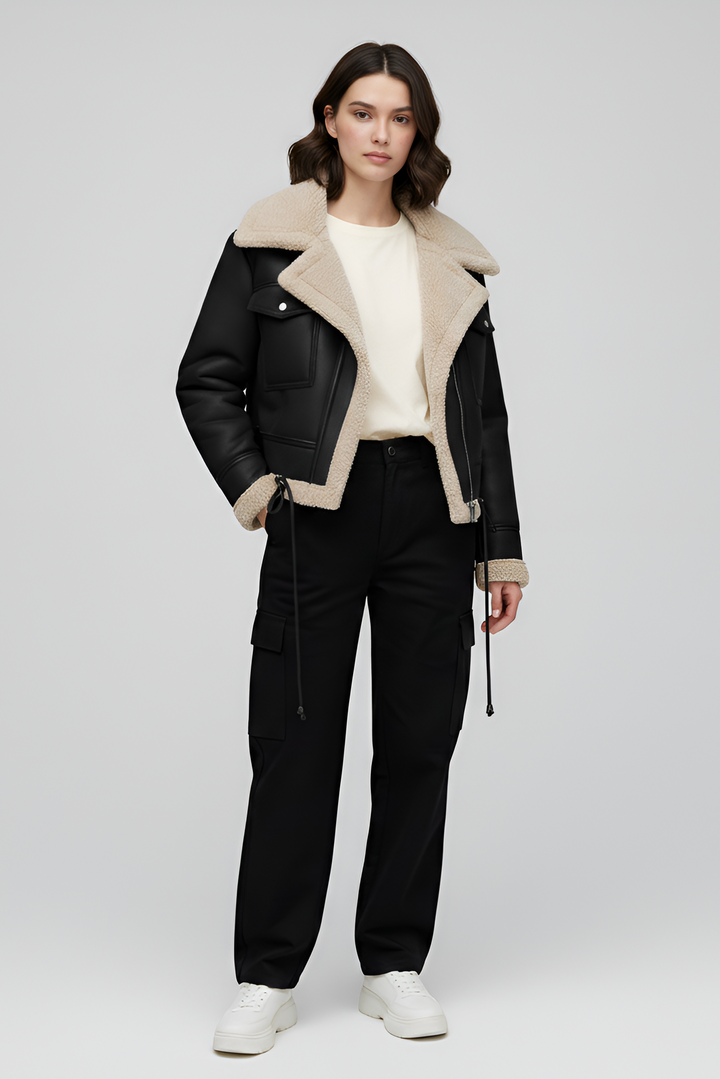 Woman wearing a black leather jacket with beige shearling lining on a white background