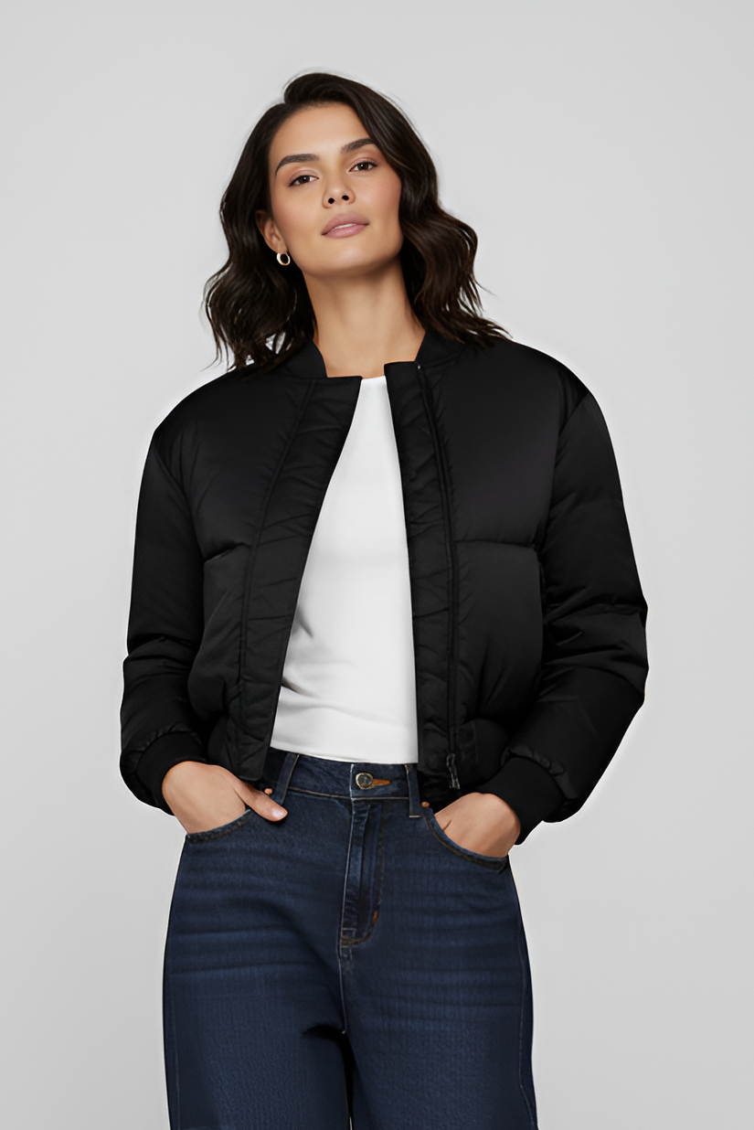 Woman wearing a black puffer jacket and dark blue cargo pants on a light gray background