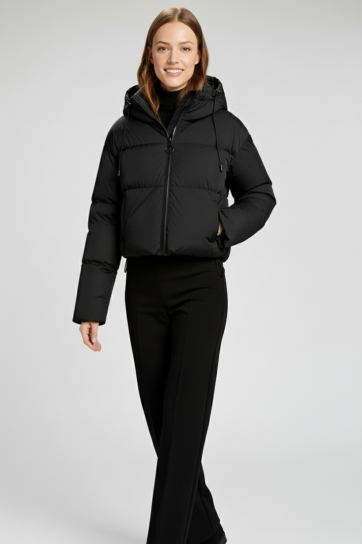 Woman wearing a black puffer jacket and pants on a white background