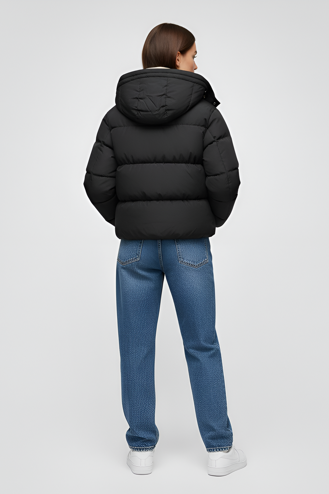 Woman wearing a black puffer jacket, black hoodie, beige cargo pants, and white sneakers on a light gray background