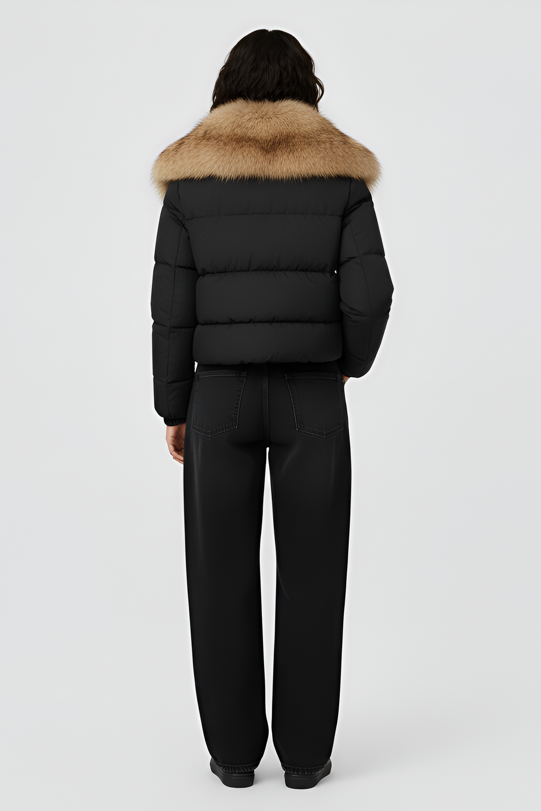 Woman wearing a black puffer jacket with a fur hood on a white background