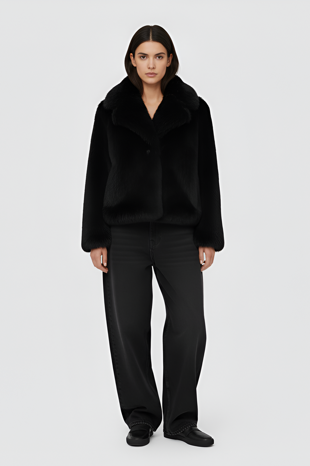 Woman wearing a black fur coat over a white outfit on a plain background