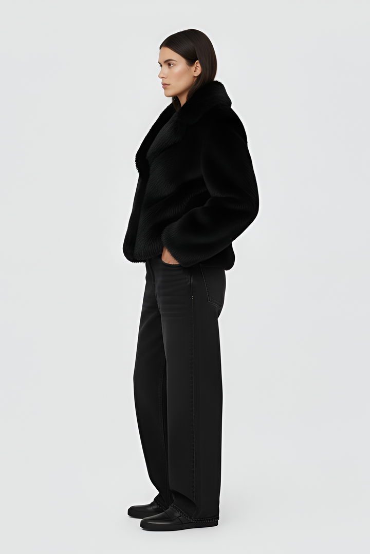 Woman wearing a black fur coat over a white outfit on a plain background