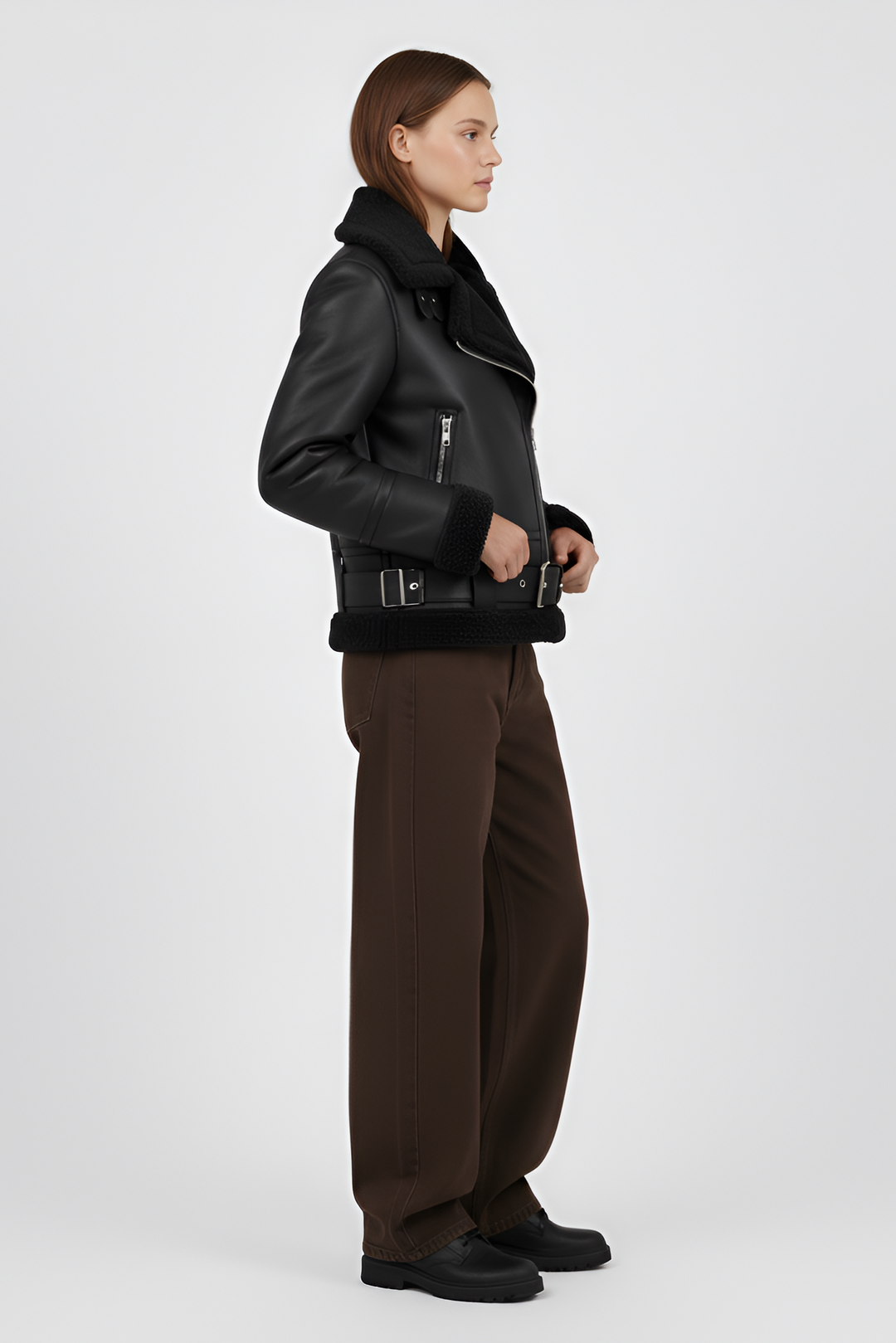 Woman wearing a black shearling jacket and pants on a light gray background