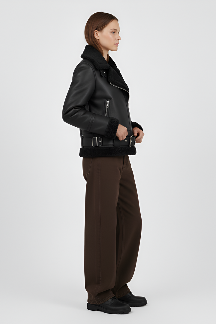 Woman wearing a black shearling jacket and pants on a light gray background