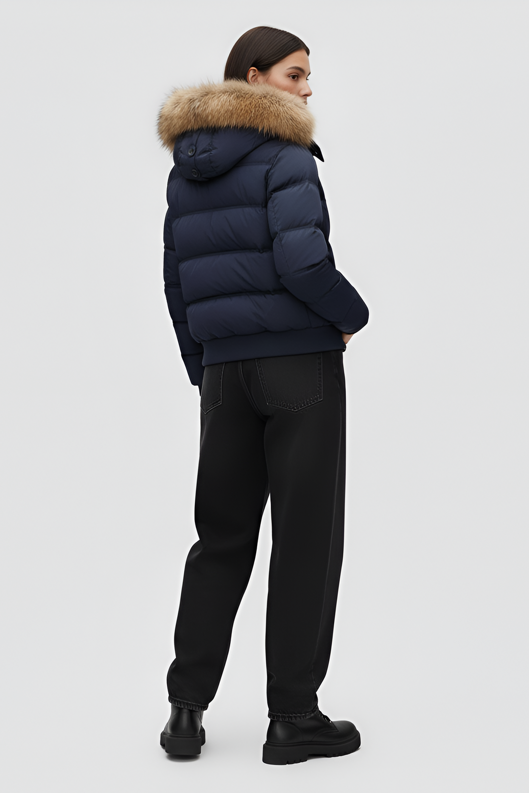 Woman wearing a blue puffer jacket, white shirt, and gray pants on a plain background