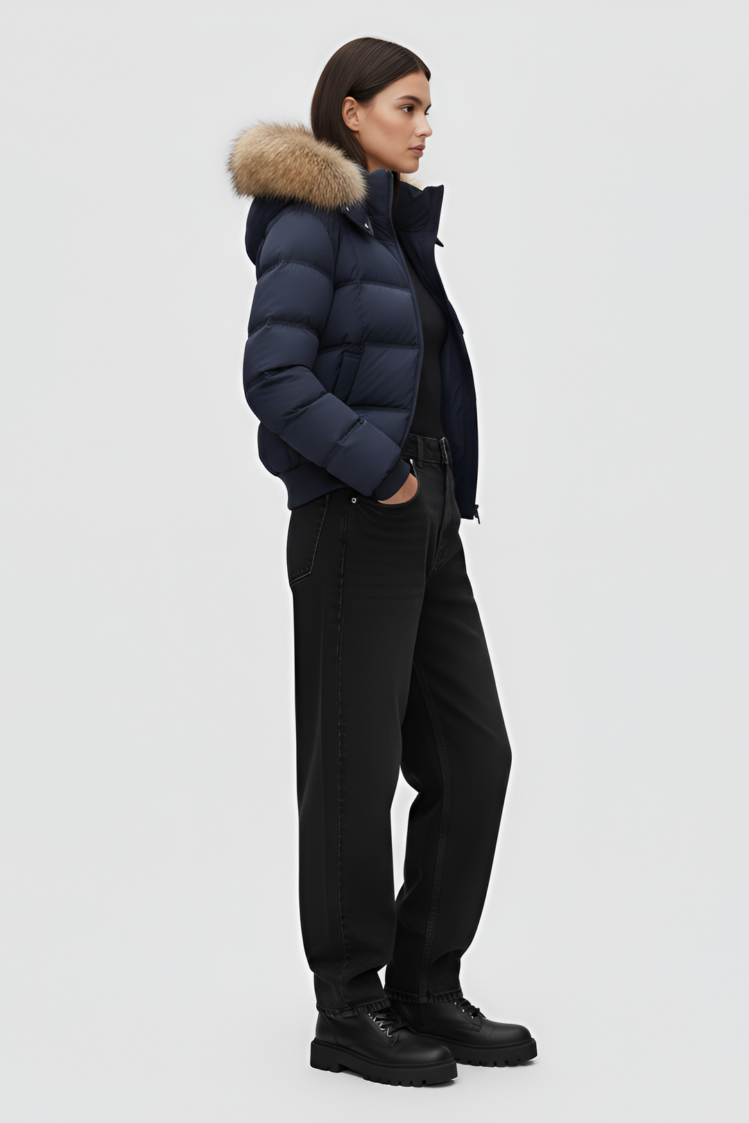 Woman wearing a blue puffer jacket, white shirt, and gray pants on a plain background