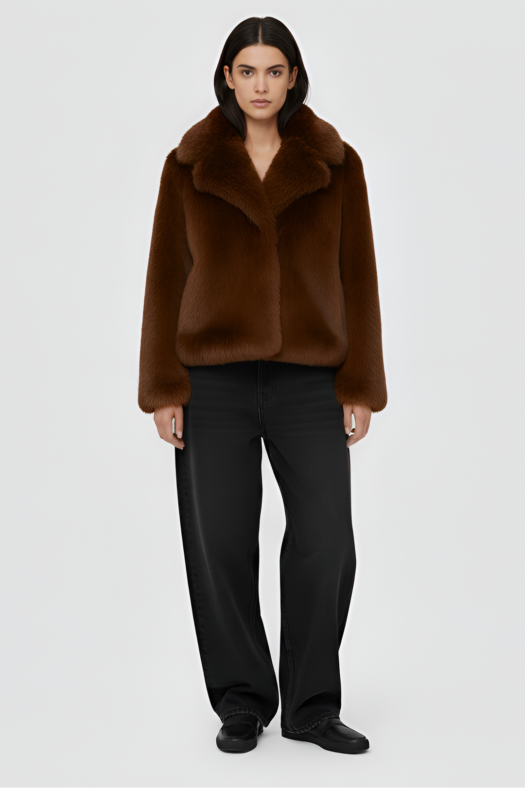 Woman wearing a brown outfit with a coat on a plain background