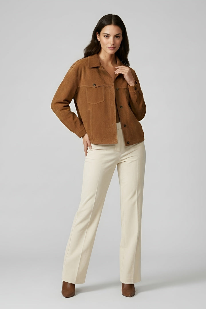 Woman wearing a brown jacket and beige pants on a plain background