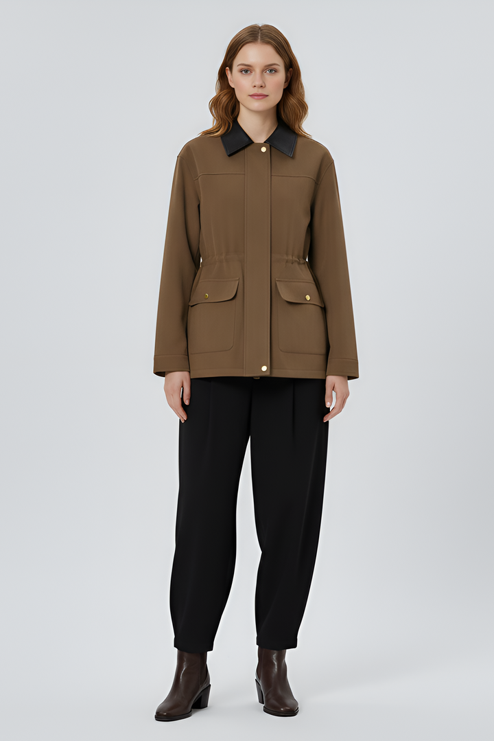 Woman wearing a brown jacket and black pants on a light gray background