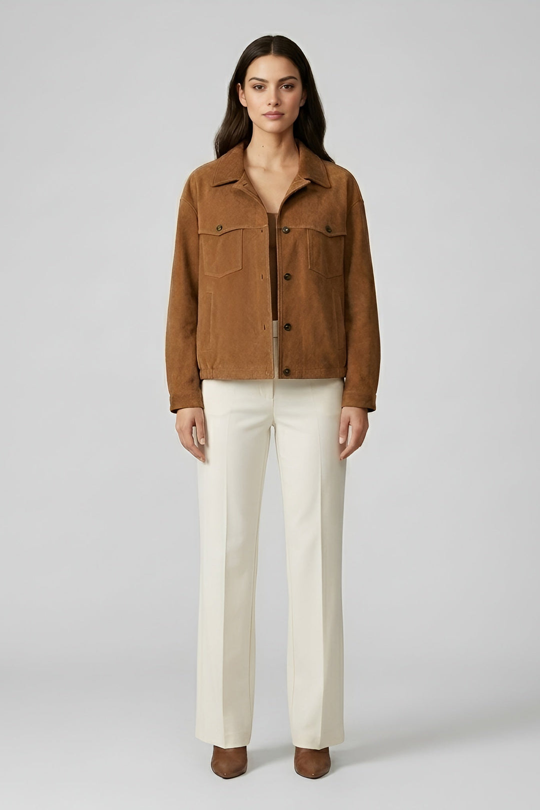 Woman wearing a brown jacket and white pants on a gray background