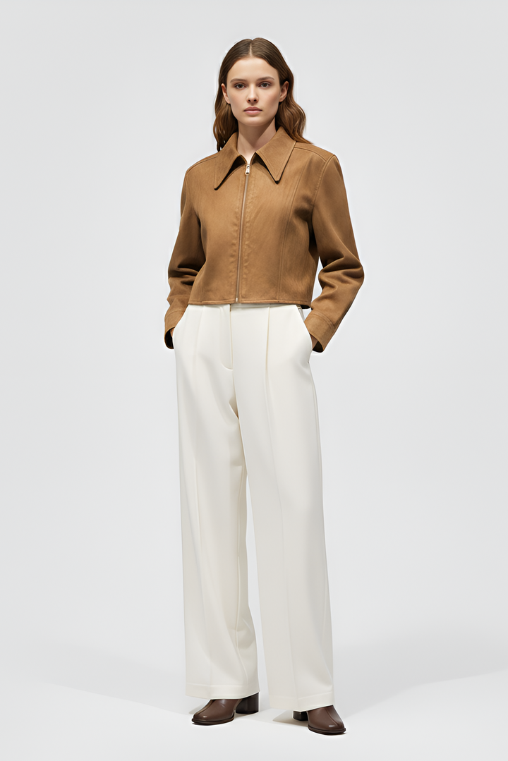 Woman wearing a brown jacket and white pants on a white background