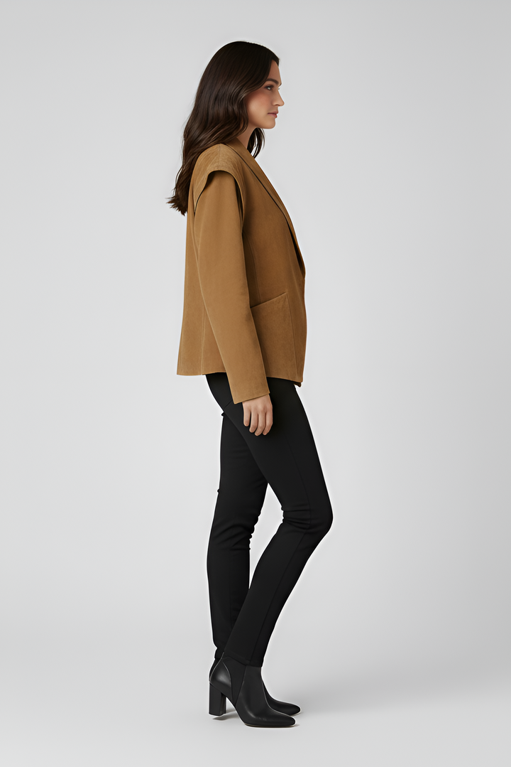 Woman wearing a brown jacket, black pants, and black boots side profile