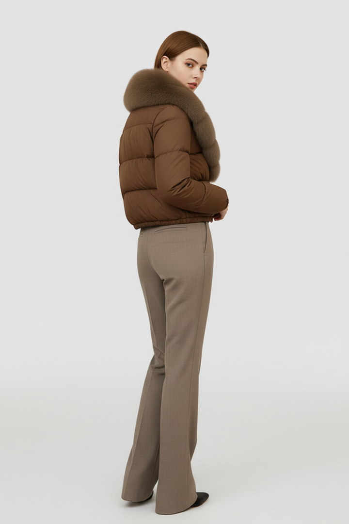Woman wearing a brown puffer jacket and beige pants on a white background