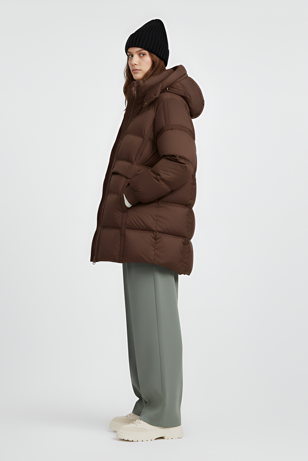 Woman wearing a brown puffer jacket on a light gray background