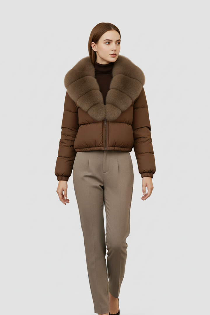 Woman wearing a brown puffer jacket with fur collar and beige pants on a white background