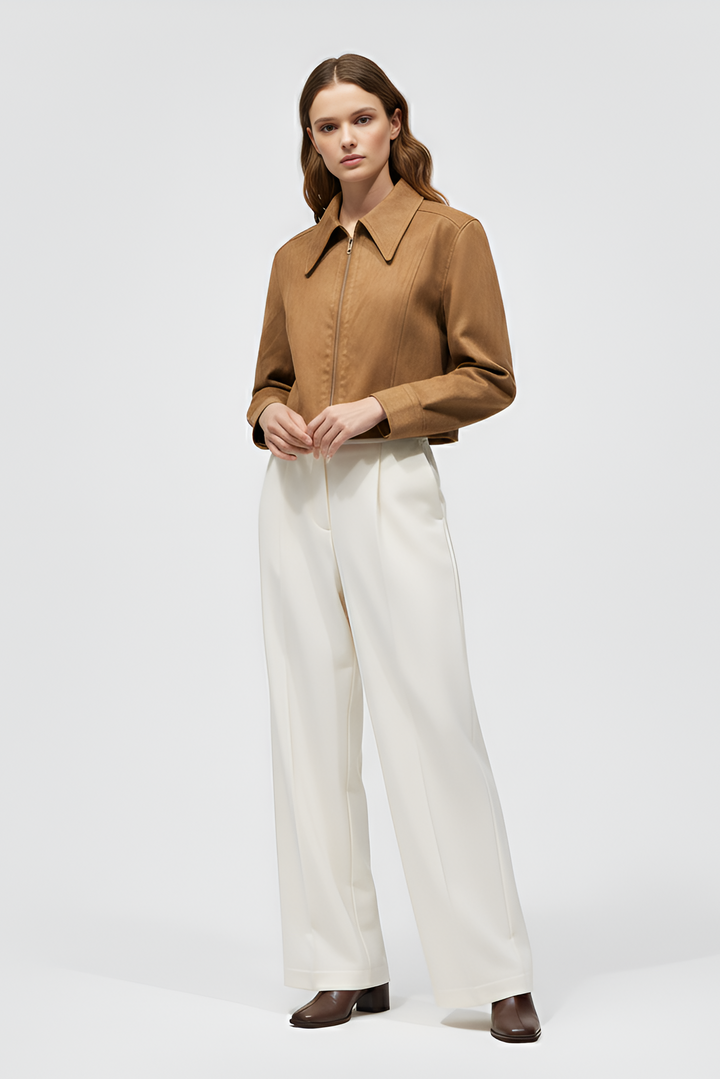 Woman wearing a brown shirt and white pants on a light gray background
