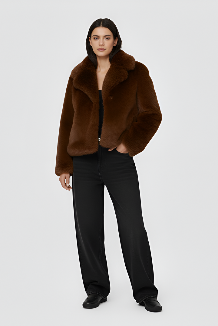 Woman wearing a brown outfit with a coat on a plain background