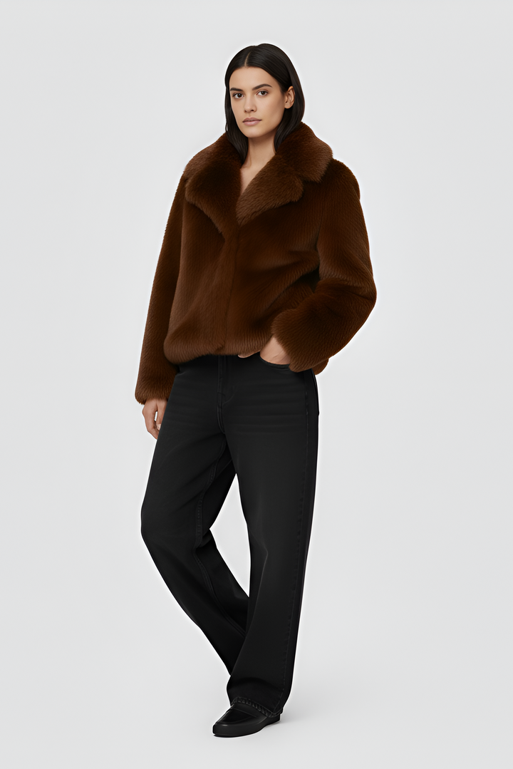 Woman wearing a brown outfit with a coat on a plain background