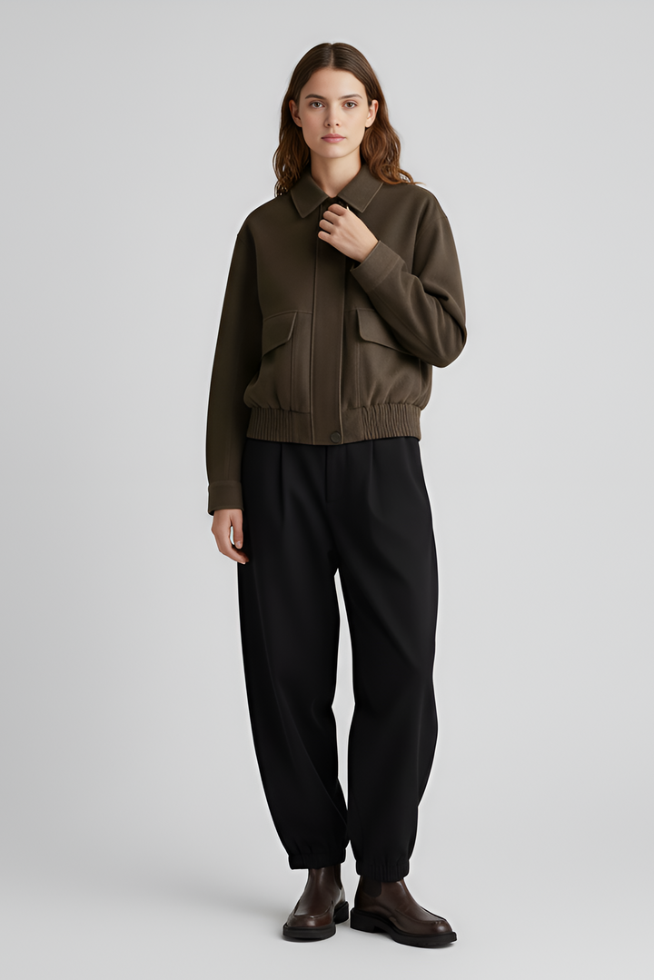 Woman wearing a brown sweater and black pants on a light gray background