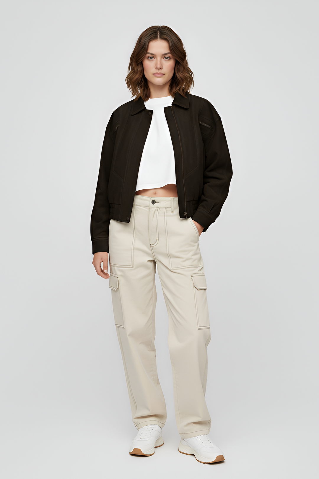 Woman wearing a brown sweater and black pants on a light gray background