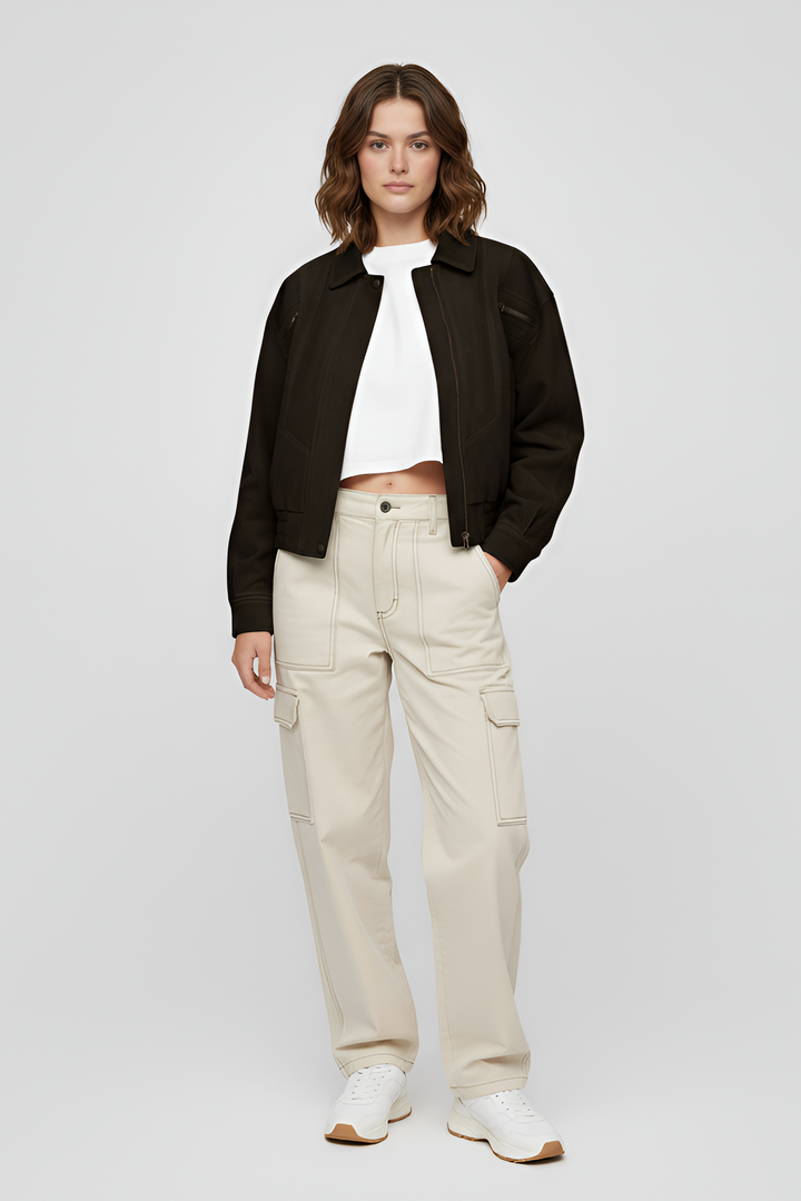 Woman wearing a brown sweater and black pants on a light gray background