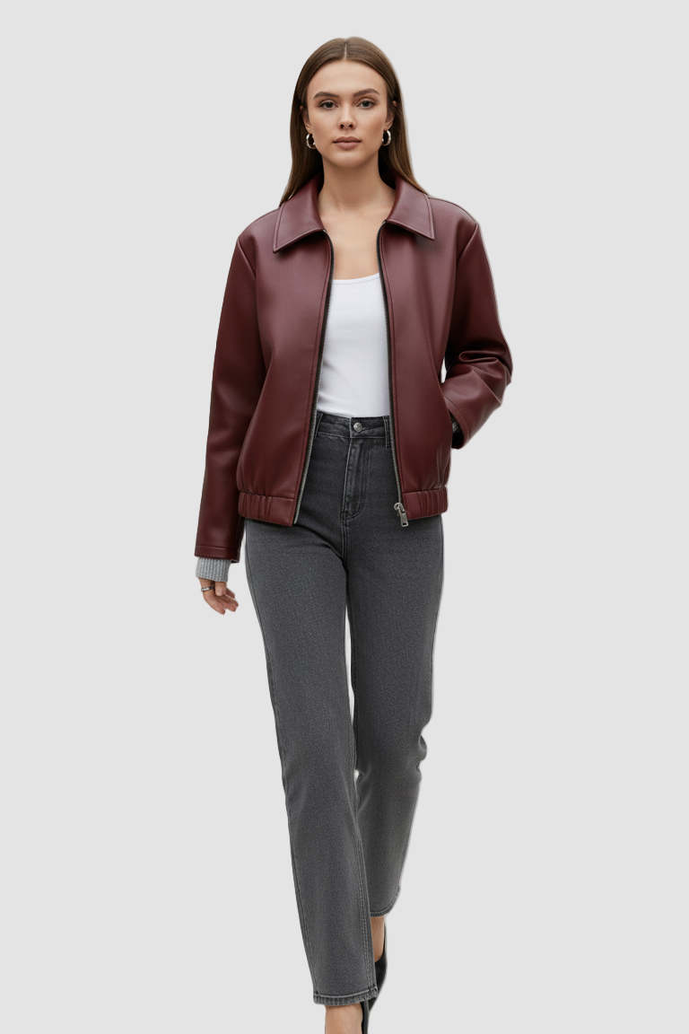 Woman wearing a burgundy leather jacket, white top, and gray pants on a white background