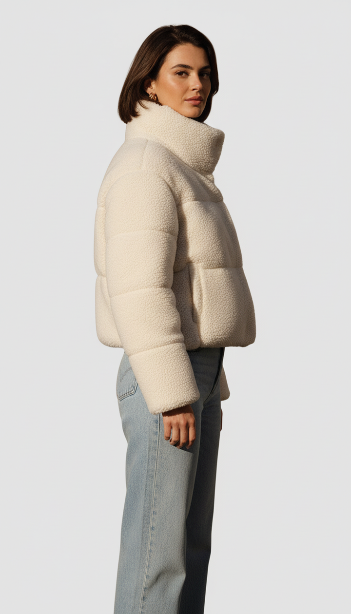 Woman wearing a cream puffer jacket against a white background