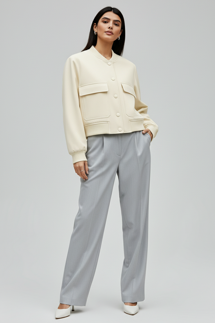 Woman wearing a cream sweater and light gray pants on a white background