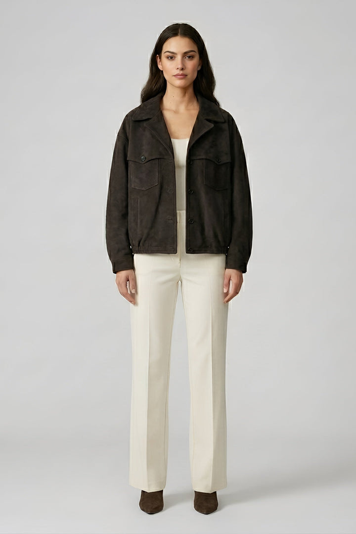 Woman wearing a dark jacket and white pants on a plain background